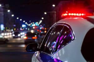 Police Car Lights At Night In City With Selective Focus And Blurry Car Traffic
