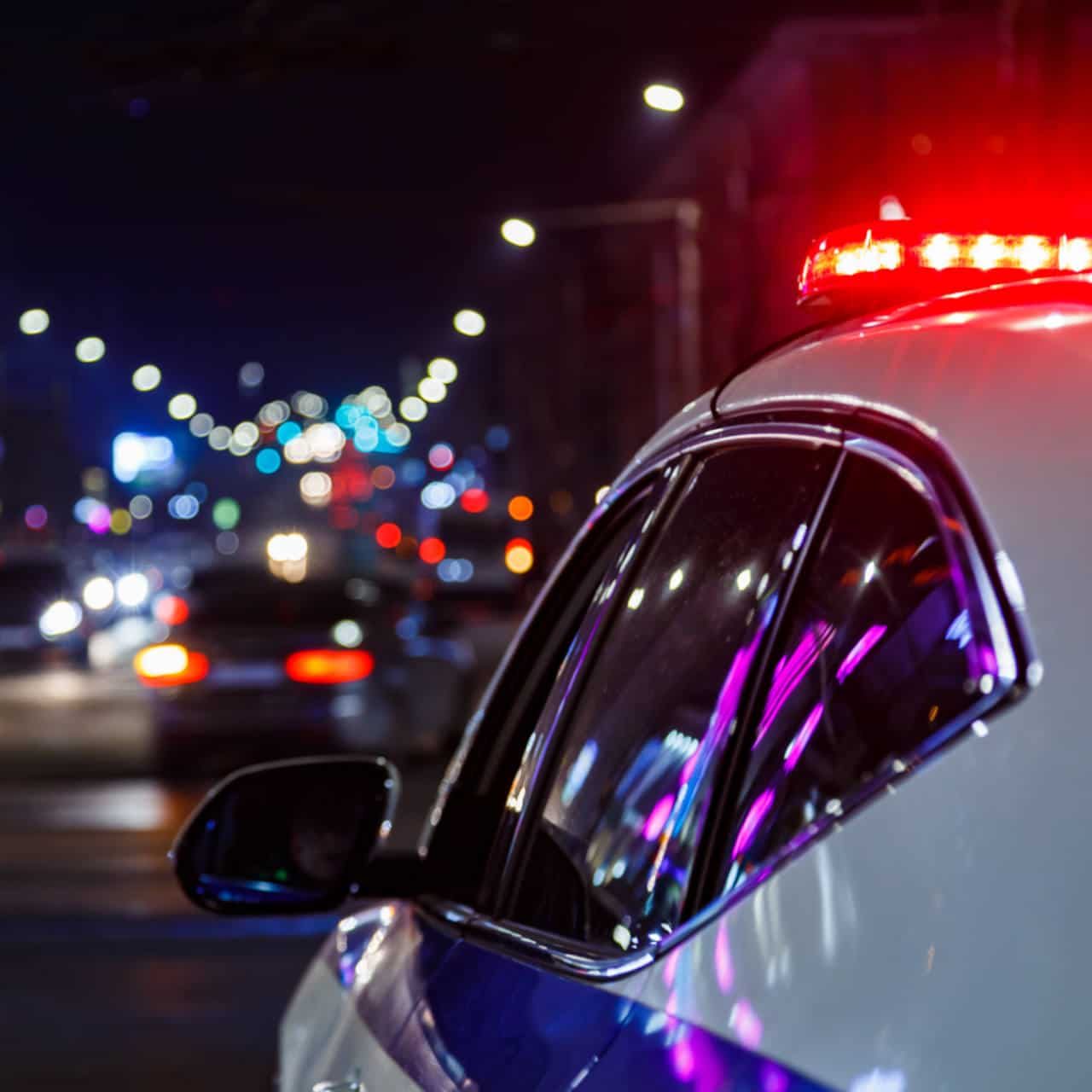 police car lights at night in city with selective focus and blurry car traffic