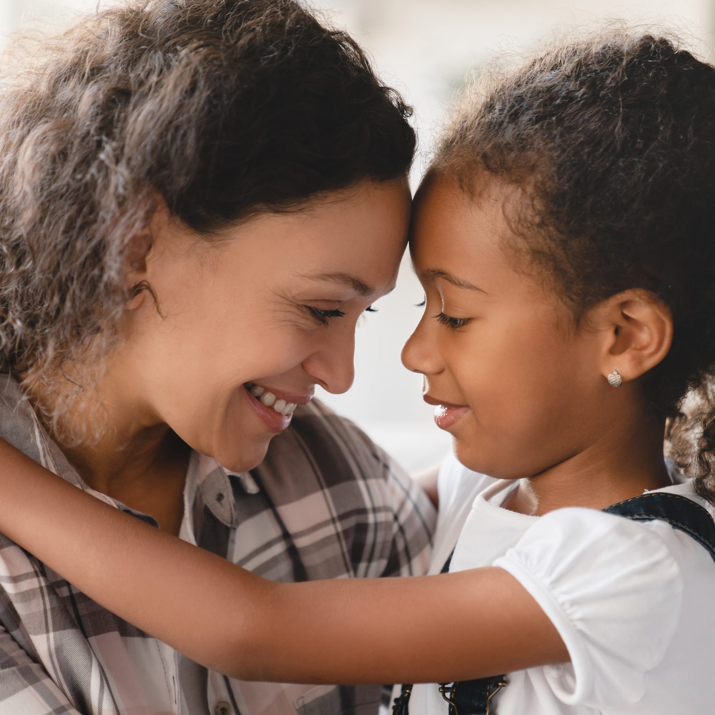 African-american mother and small little young preteen daughter hugging embracing with eyes closed sharing love and care.